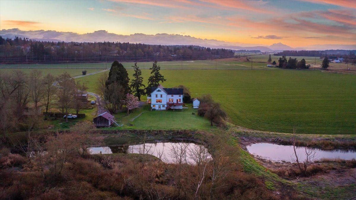 Aerial sunrise over a farmhouse on Marine Drive in Stanwood, WA with pasture and pond
